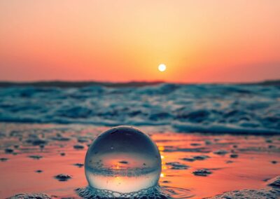 Une bulle d'eau posée sur le bord de mer, devant un superbe coucher de soleil orange et doré.