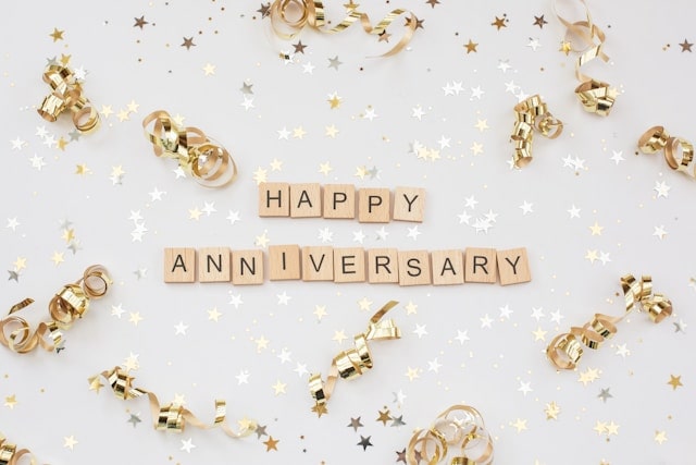 Bannière de décoration blanche et dorée, avec les inscriptions "Happy anniversary" pour l'anniversaire d'une entreprise