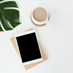 Tablette d'ordinateur entourée d'une jolie feuille verte et d'une tasse de thé