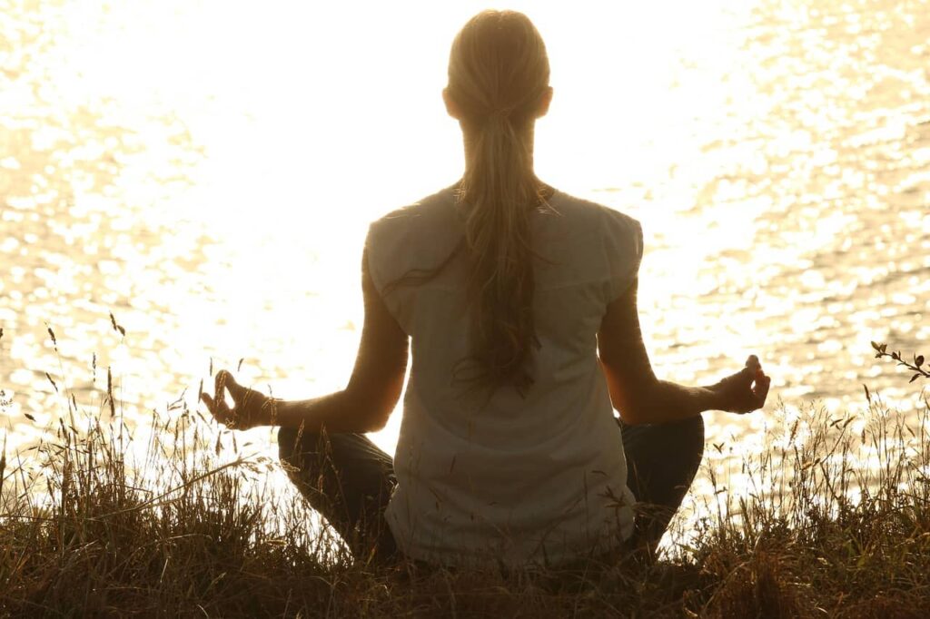 Yoga en plein air face au coucher du soleil Femme en séance de yoga et méditation en plein air, devant le coucher du soleil