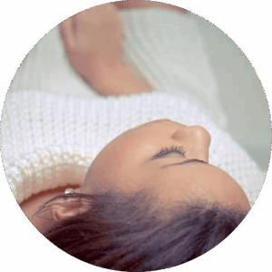 Femme brune portant un pull blanc, en pleine méditation
