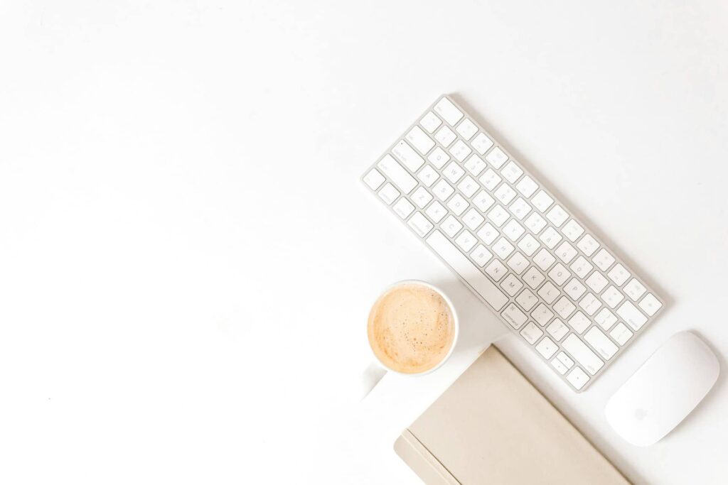 Clavier et souris d'ordinateur, agenda papier et tasse de cappuccino prêts à être utilisés pour organiser un événement de bien-être holistique